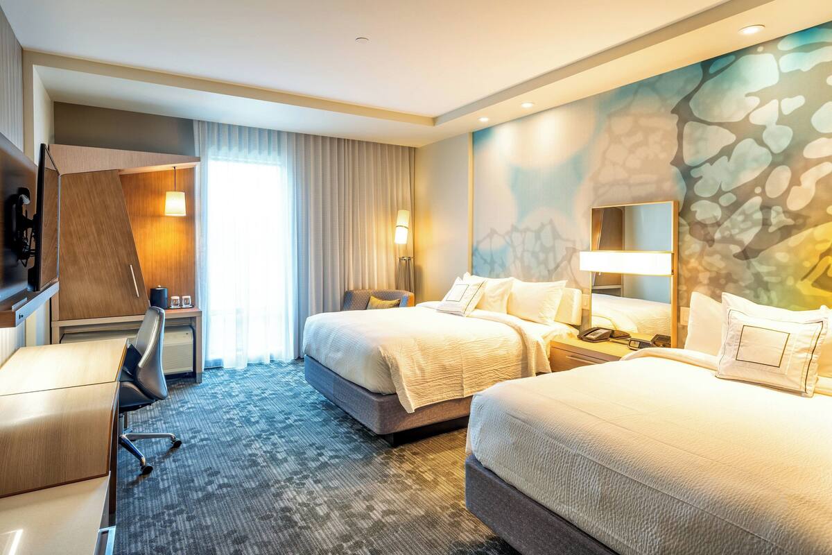 Ein Hotelzimmer mit zwei Betten, einem Schreibtisch und einem Stuhl.