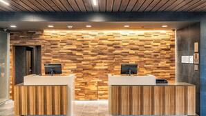 Een receptie met twee houten balies, een wand met een houten plankenpatroon en een plafond met houten latten.