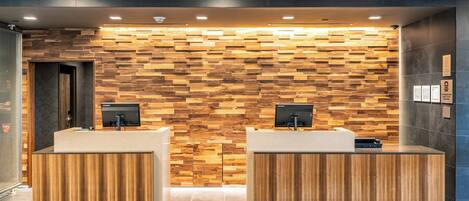 Un área de recepción con dos mostradores de madera, una pared con diseño de tablones y un techo con listones de madera.