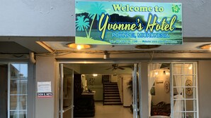 Yvonne's -hotellin sisäänkäynti Pohneissa, Mikronesian alueella. Siinä on ystävällinen tervetulokyltti, vastaanottoalue ja portaikko, joka johtaa hotellin sisätiloihin.