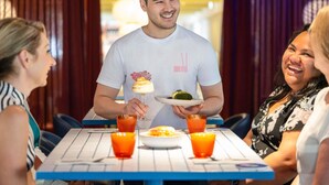 A person serving food at a table with orange glasses and a dessert. - ibis Styles Pforzheim (Pforzheim)