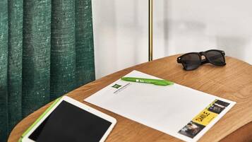 Una mesa de madera con una tableta, un bolígrafo verde, un par de gafas de sol y un documento impreso.