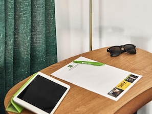 A wooden table with a tablet, a green pen, a pair of sunglasses, and a printed document. - ibis Styles Pforzheim (Pforzheim)