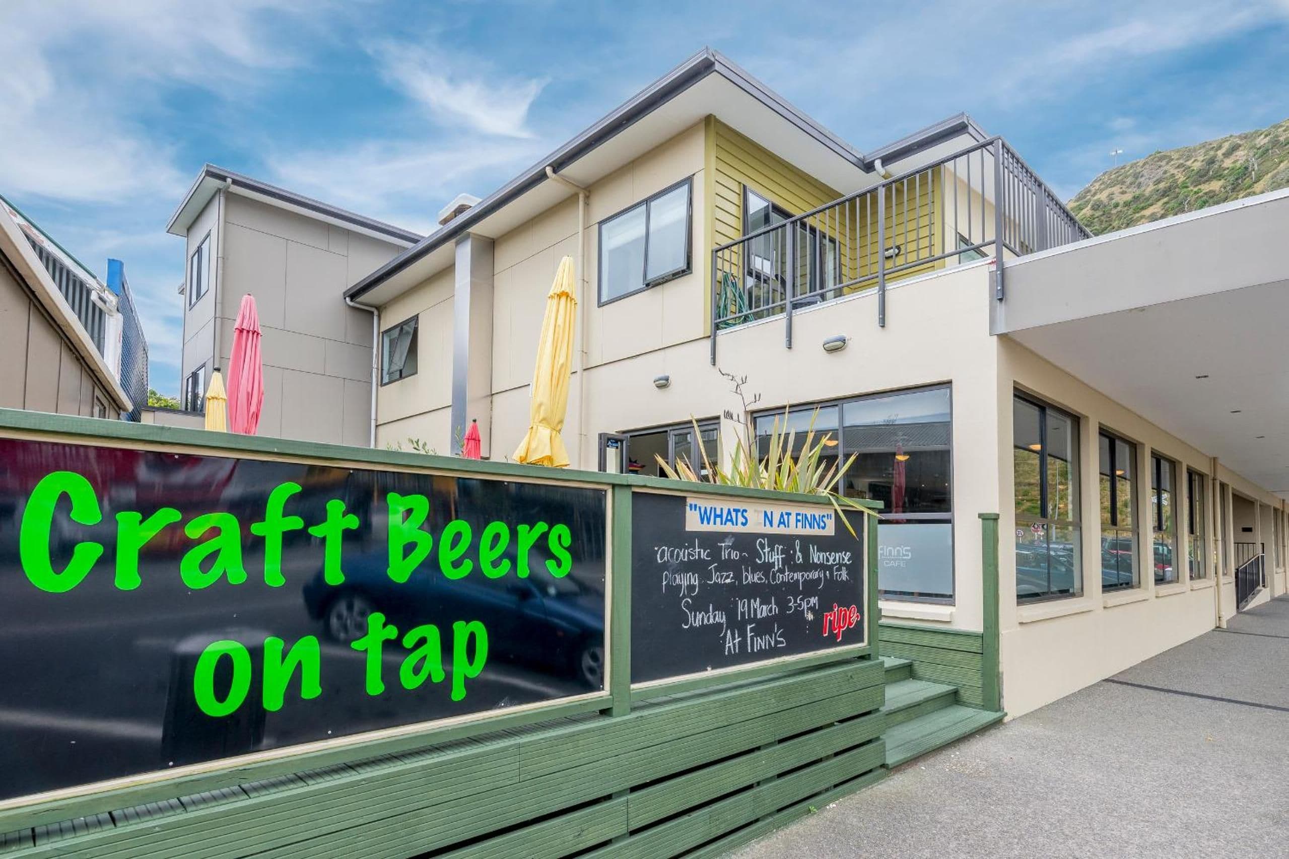 En bygning med et skilt, der siger 'Craft Beers på fad', og et andet skilt, der reklamerer for 'Hvad der sker hos Finns' med en liste over musikgenrer, dato og tidspunkt.