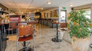 A spacious restaurant with high tables and chairs, a bar area, and a large potted plant. - Finns (Paekakariki)