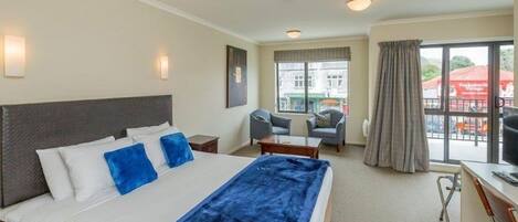 Habitación de hotel con una cama grande, un escritorio, una silla y una ventana con cortinas.