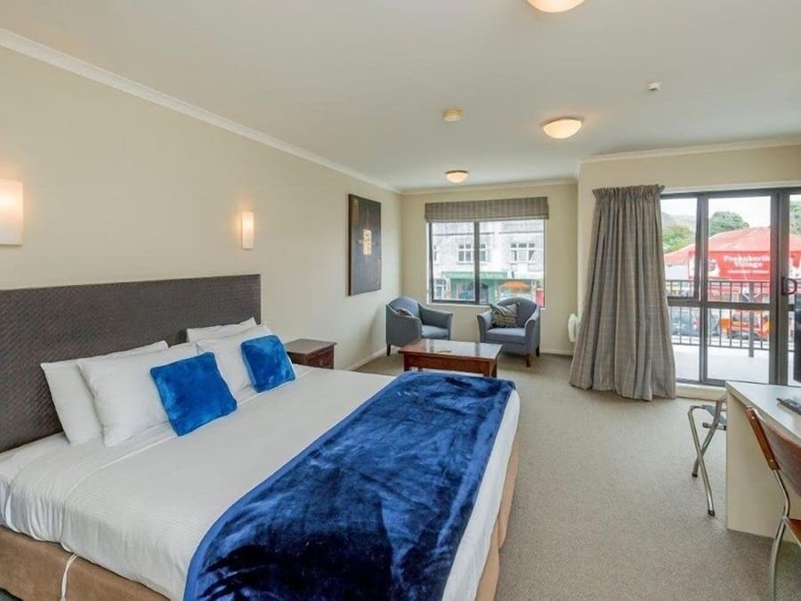 Habitación de hotel con una cama grande, un escritorio, una silla y una ventana con cortinas.