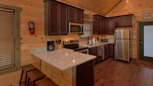A kitchen with wooden cabinets, a stainless steel refrigerator, a coffee maker, and a fire extinguisher.