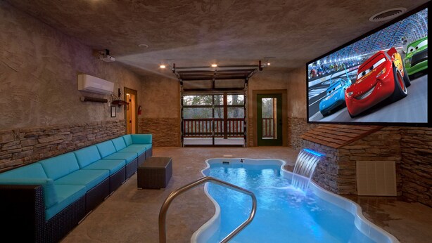 A spa area with a pool, a blue sofa, and a television displaying animated cars.
