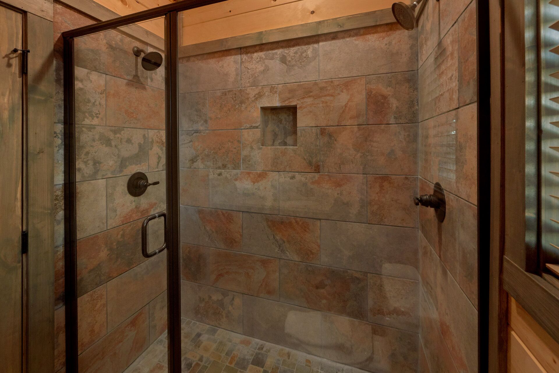 Dusche mit Steinfliesen und Glastür.