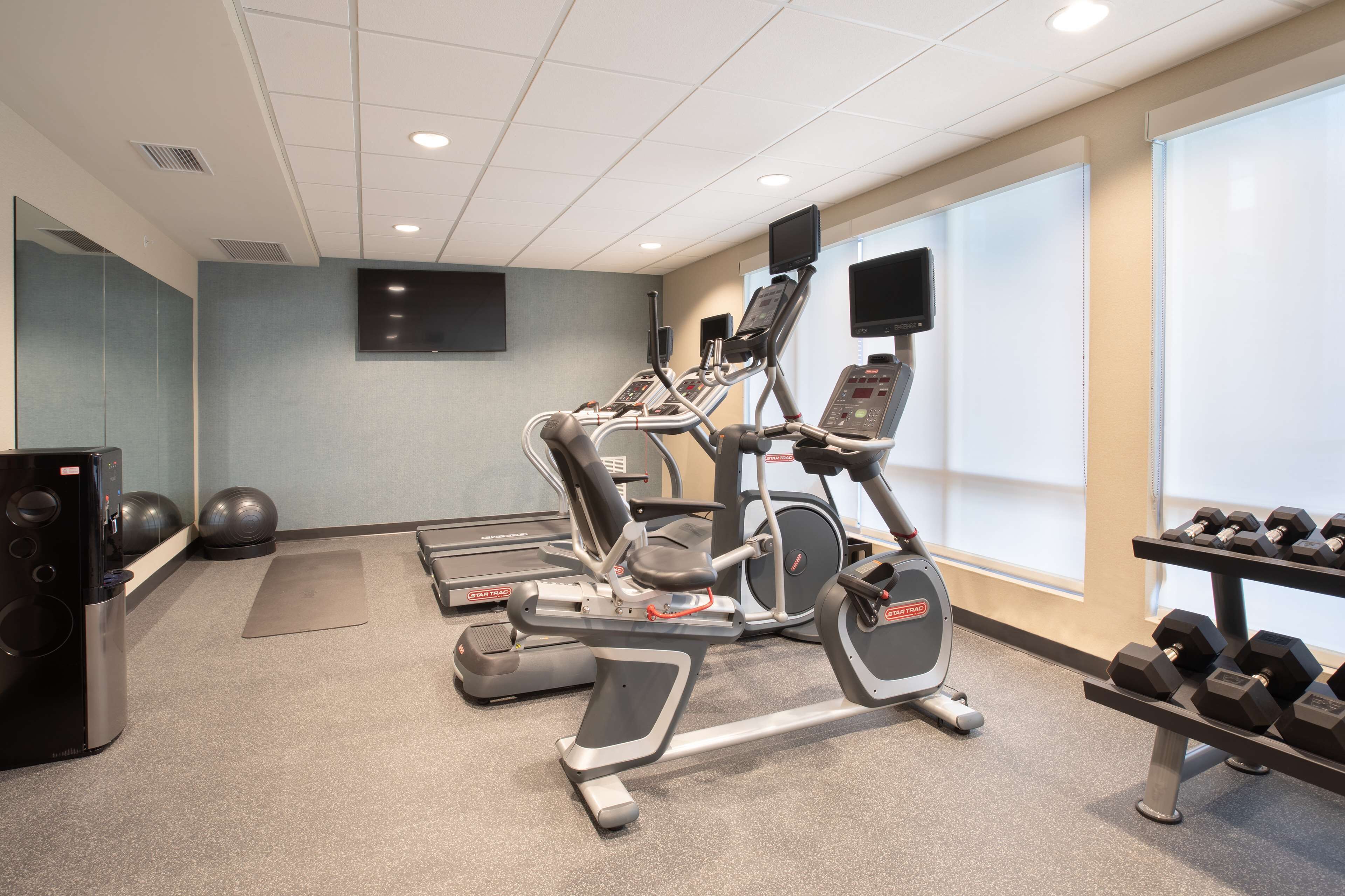 A gym with treadmills, ellipticals, and a weight bench.