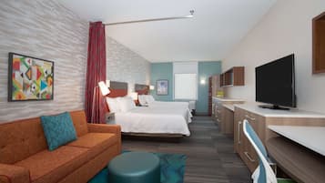 A hotel room with a bed, a sofa, a TV, and a desk.