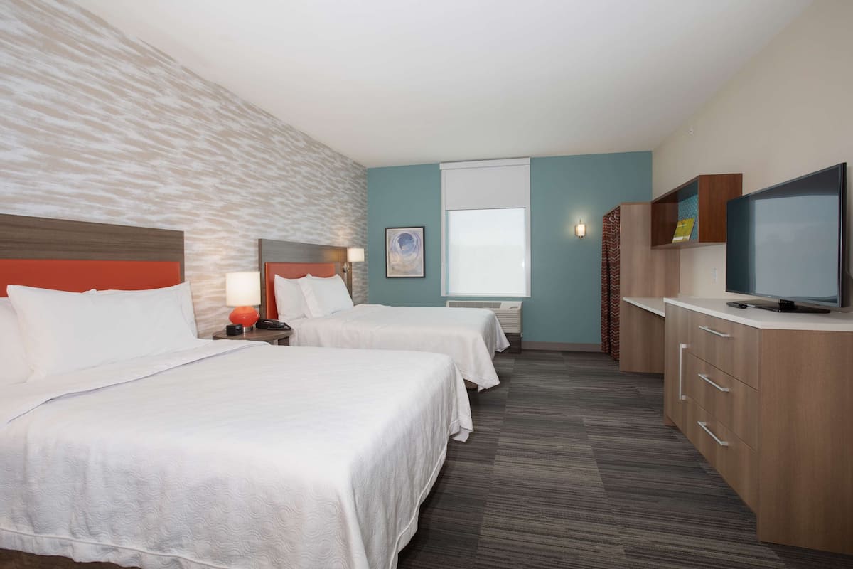 Een hotelkamer met twee bedden, een televisie, een bureau en een raam.