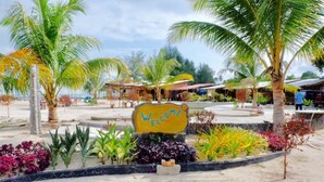 A tropical resort with a 'Welcome' sign, palm trees, and a beach area. - Hello Bintan Beach Cottages (Bintan)