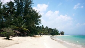 A beach with clear turquoise water, palm trees, and a sandy shore. - Hello Bintan Beach Cottages (Bintan)