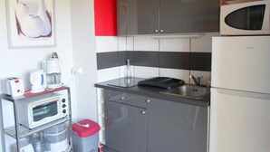 Ett kompakt kök med en mikrovågsugn, brödrost och kaffebryggare på en bänkskiva.