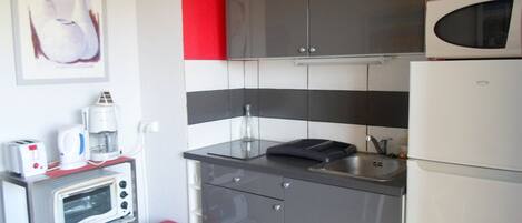 A compact kitchen with a microwave, toaster, and coffee maker on a countertop.