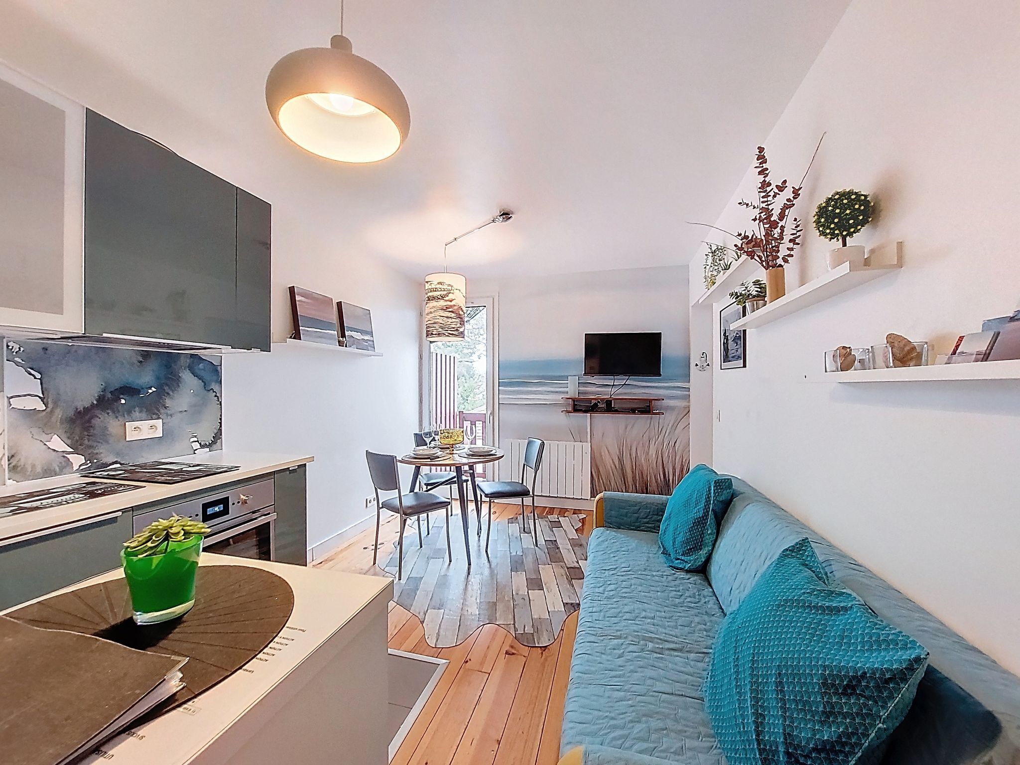 A modern living room with a sofa, dining table, and kitchen area.
