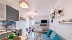 Een moderne woonkamer met een bank, eettafel en keukenhoek.