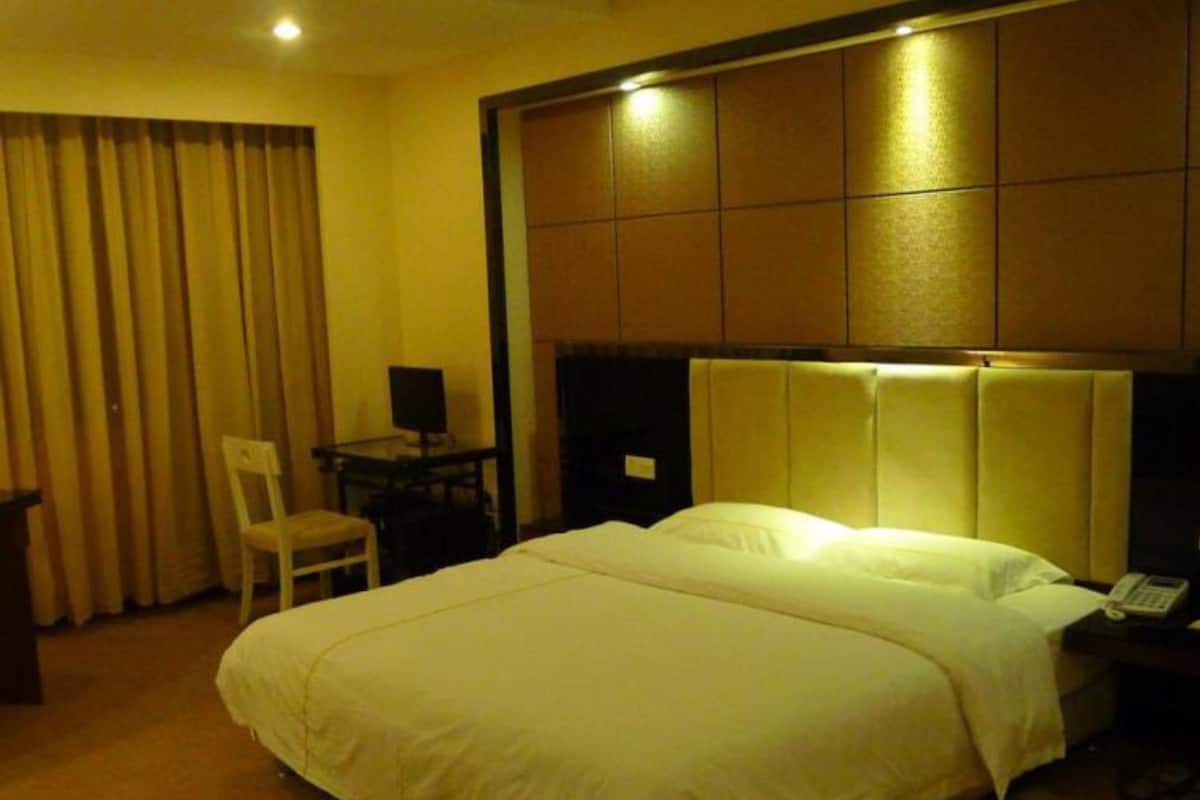 Una habitación de hotel con una cama grande, un escritorio con una silla y una mesita de noche con teléfono.