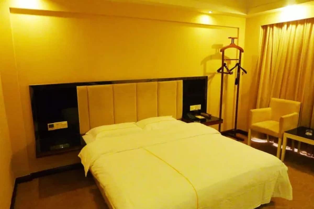 Habitación de hotel con una cama grande, una mesita de noche con teléfono, una silla y un perchero.