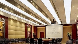 A conference room with a large screen, rows of chairs, and a podium. - Junyue Hotel (Zhaoqing)