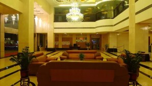 A spacious lobby with a large sofa, potted plants, and a grand chandelier. - Junyue Hotel (Zhaoqing)