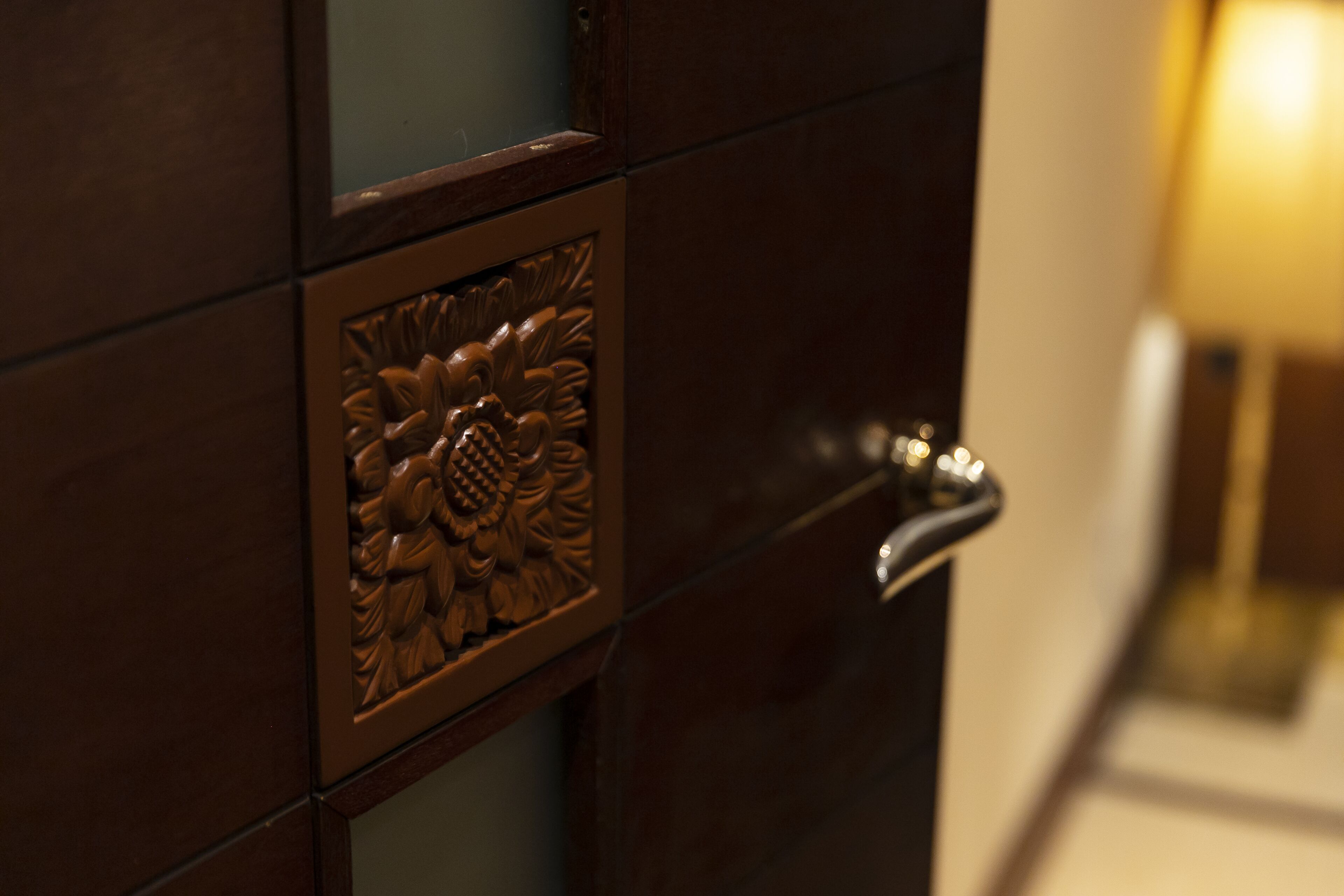 Primer plano de una puerta con un panel decorativo y un pomo moderno.