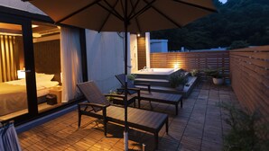 Un patio con mobiliario de mimbre, una sombrilla grande y una terraza de madera.