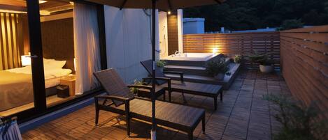 A patio with wicker furniture, a large umbrella, and a wooden deck.