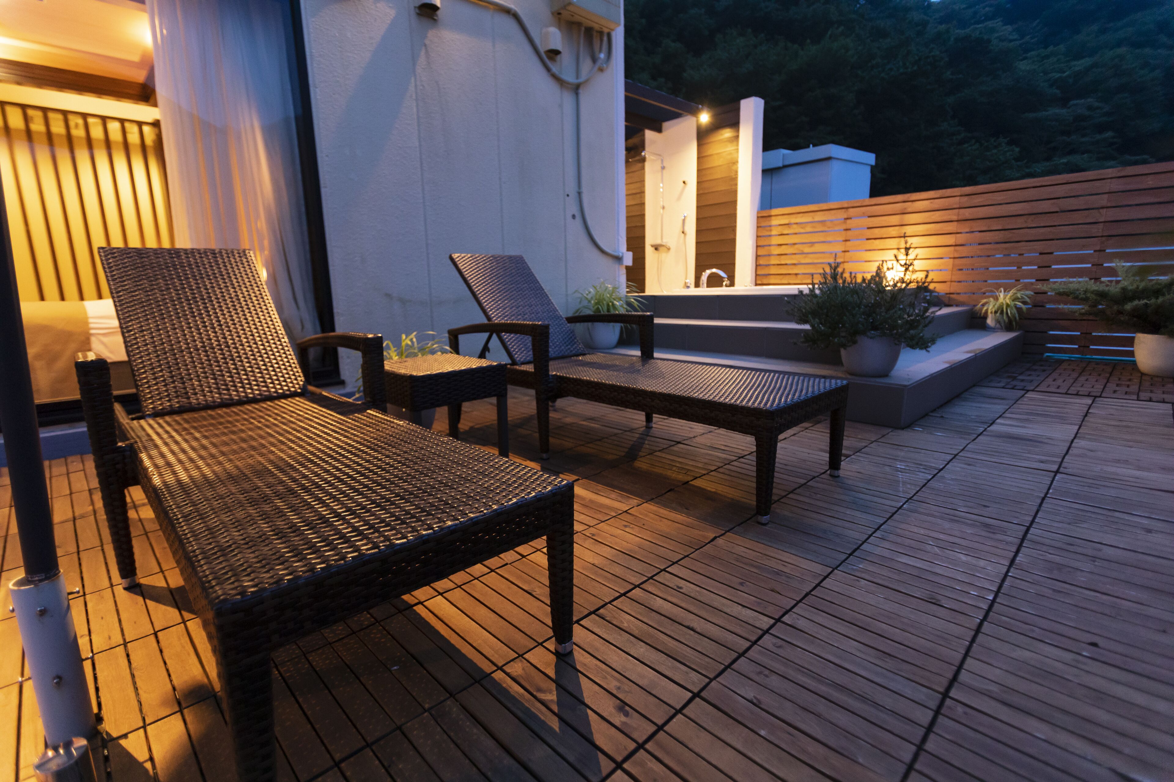 Une terrasse en bois avec des meubles en osier et des plantes en pot.