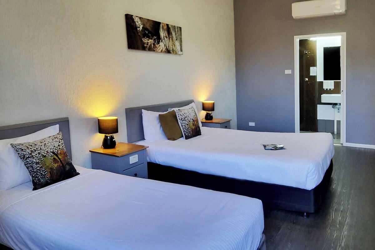 Two single beds with white linens, wooden nightstands, and table lamps.