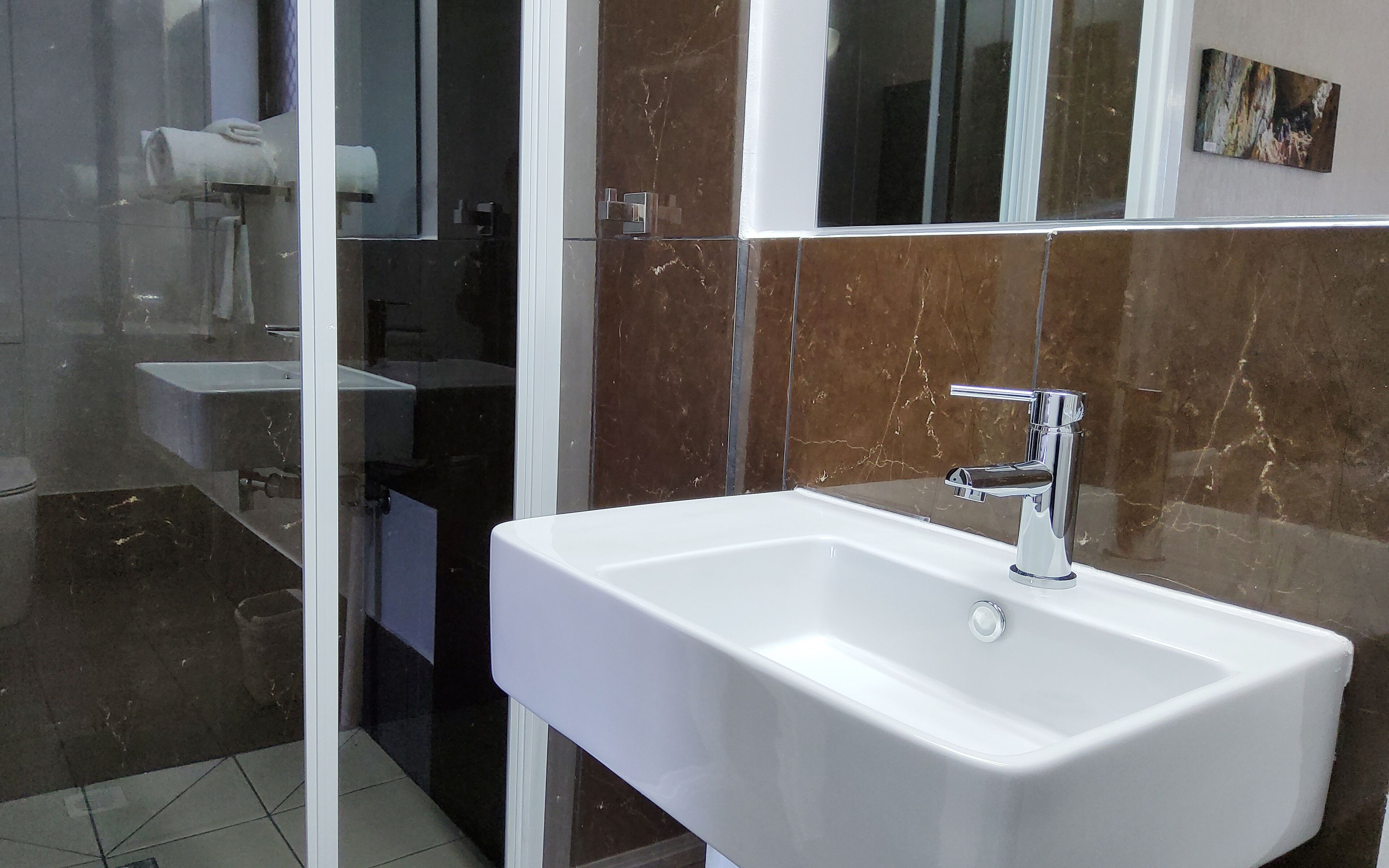 Un baño con un lavamanos blanco, un espejo y una cabina de ducha de vidrio.