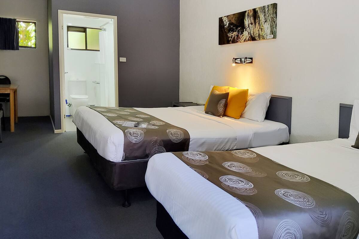 A hotel room with two beds, a desk, and a bathroom.