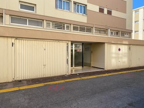 Un bâtiment à la façade beige, doté de grandes portes de garage et d’une petite entrée avec une porte en verre.