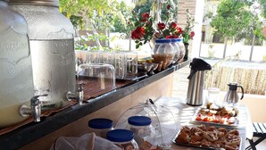 Una mesa de bufé con diversos alimentos, como pan, pasteles y salsas.
