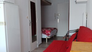 A compact room with a bed, a wooden chair, and a small table. - Comfortable 2-star studio near spa, pets allowed (Balaruc-les-Bains)