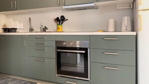 Eine moderne Küche mit grauen Schränken, Edelstahlgeräten und einer weißen Arbeitsplatte.