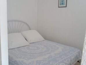 Un dormitorio con cama, dos almohadas, cabecero y un cuadro en la pared.