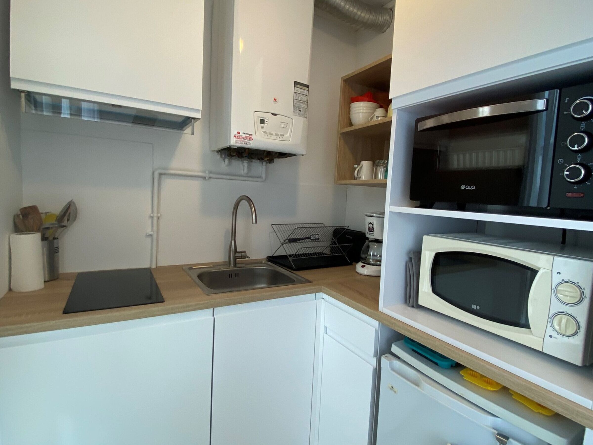 A compact kitchenette with a sink, a coffee maker, a microwave, and a toaster.