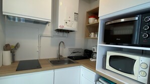 A compact kitchenette with a sink, a coffee maker, a microwave, and a toaster.