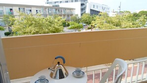 A balcony with a table set for two, a kettle, and two cups.
