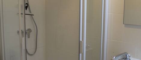 A bathroom with a glass-enclosed shower, a white sink with a chrome faucet, and a mirror on the wall.