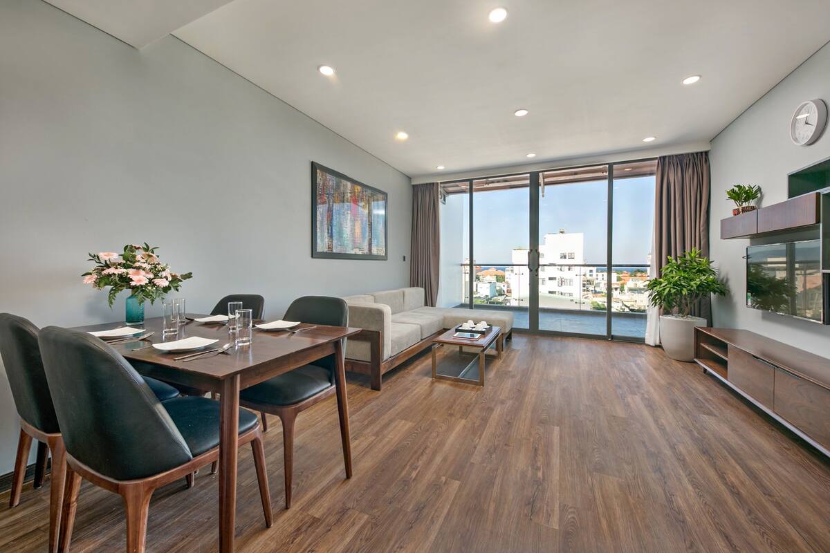 Ein modernes Wohnzimmer mit Essbereich, großen Fenstern und Blick auf die Stadt.