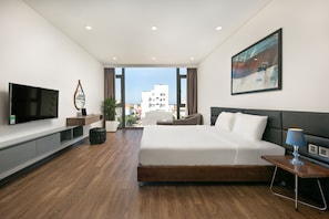 Ein modernes Hotelzimmer mit einem großen Bett, einem Flachbildfernseher, einem Gemälde und Blick auf die Stadt.