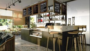A modern bar area with a counter, stools, and menu boards.