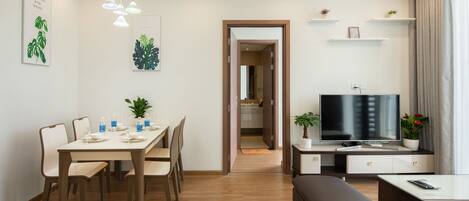 A modern living room with a dining area, a TV, and a bench.