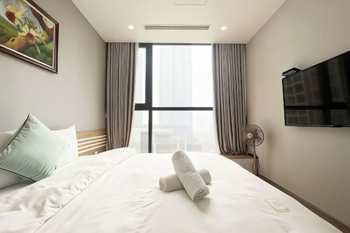 Una camera d'albergo con un letto, un quadro, una televisione e una finestra con tende.
