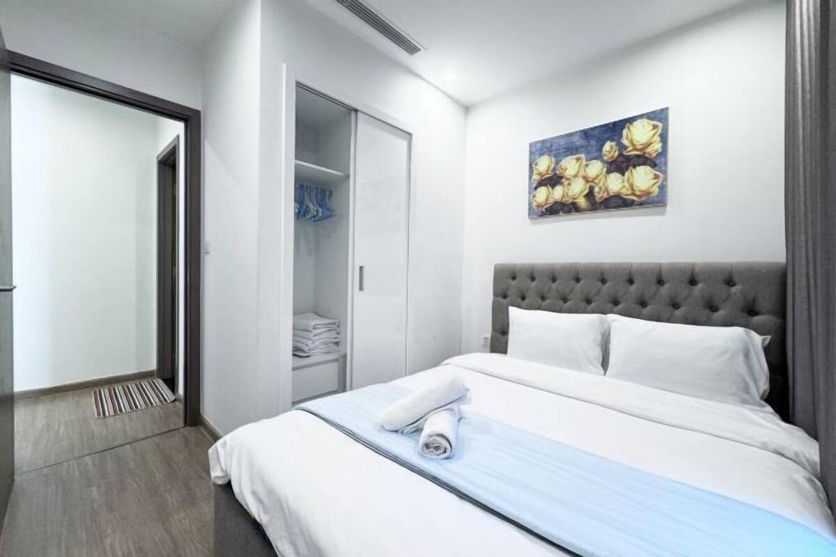 A hotel room with a bed, a wardrobe, and a painting on the wall.