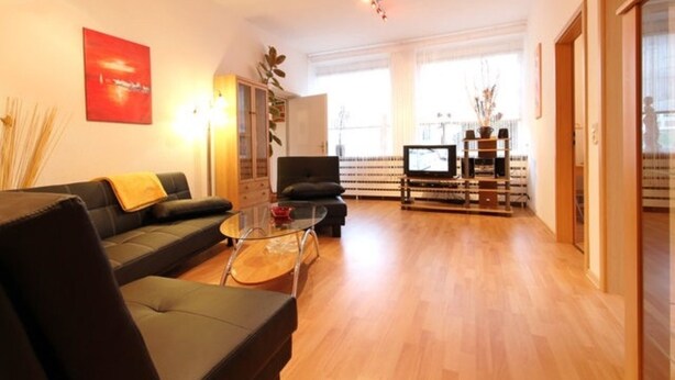 Een moderne woonkamer met een bank, een glazen salontafel en een televisie.